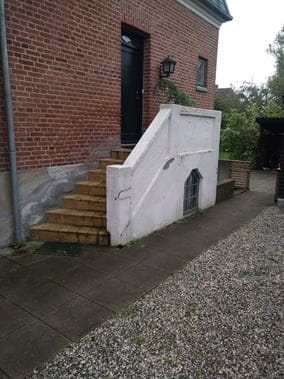 Murtrappe fører op til sort dør på murstenshus