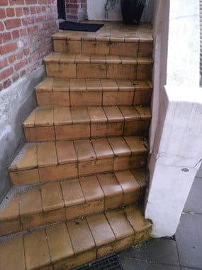 Udendørs trapper med brune fliser og murstensvæg