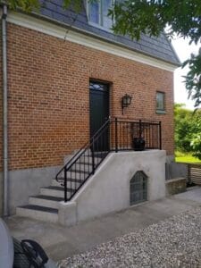 Brick house with black door and stair railings