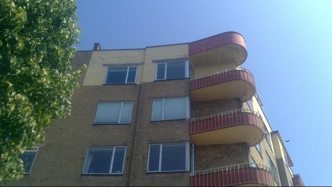 Mursten bygning med røde altaner under blå himmel