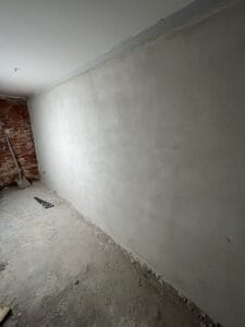 Unfinished room with plastered wall and rough floor