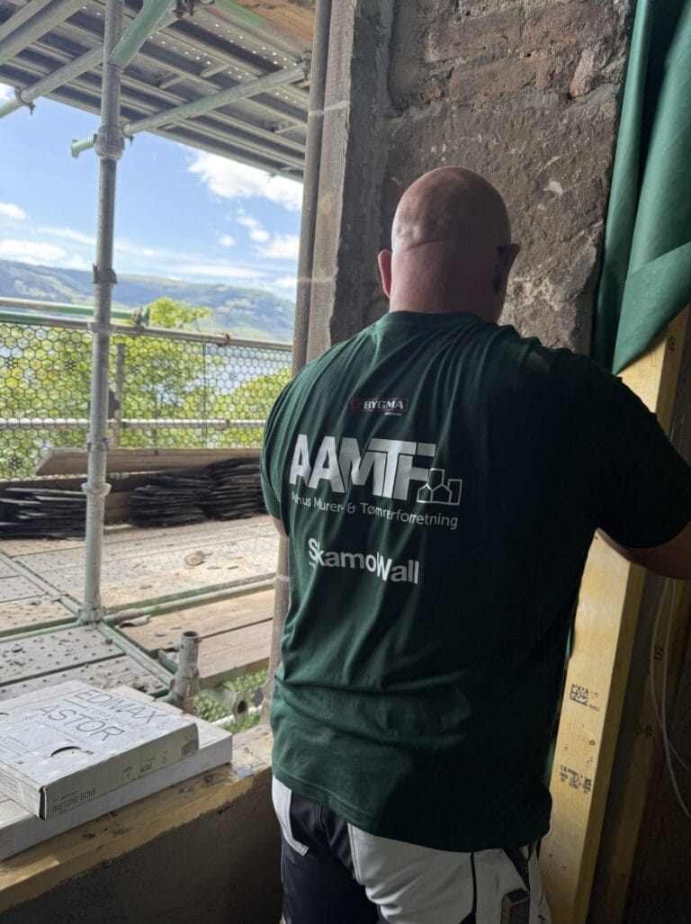 Håndværker arbejder på byggeplads med udsigt over vand.